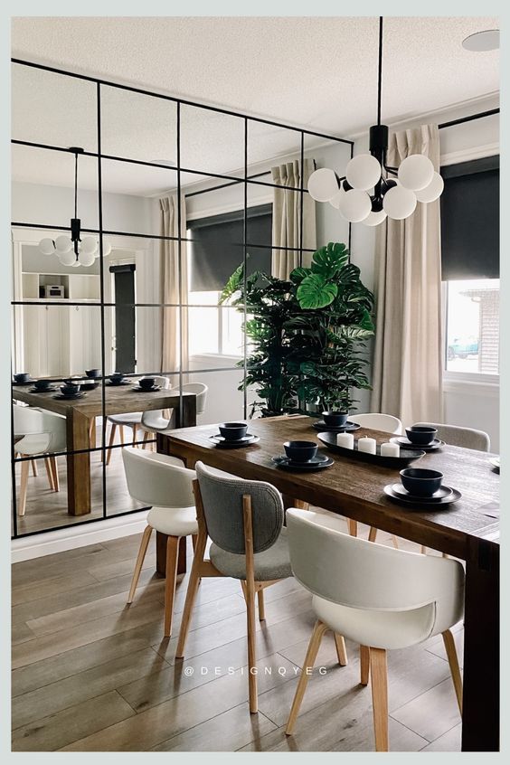 a dining room table with chairs and a large mirror in the back wall behind it