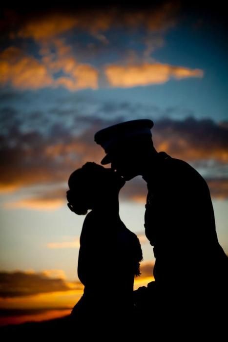 the silhouette of two people kissing in front of an orange and blue sky at sunset