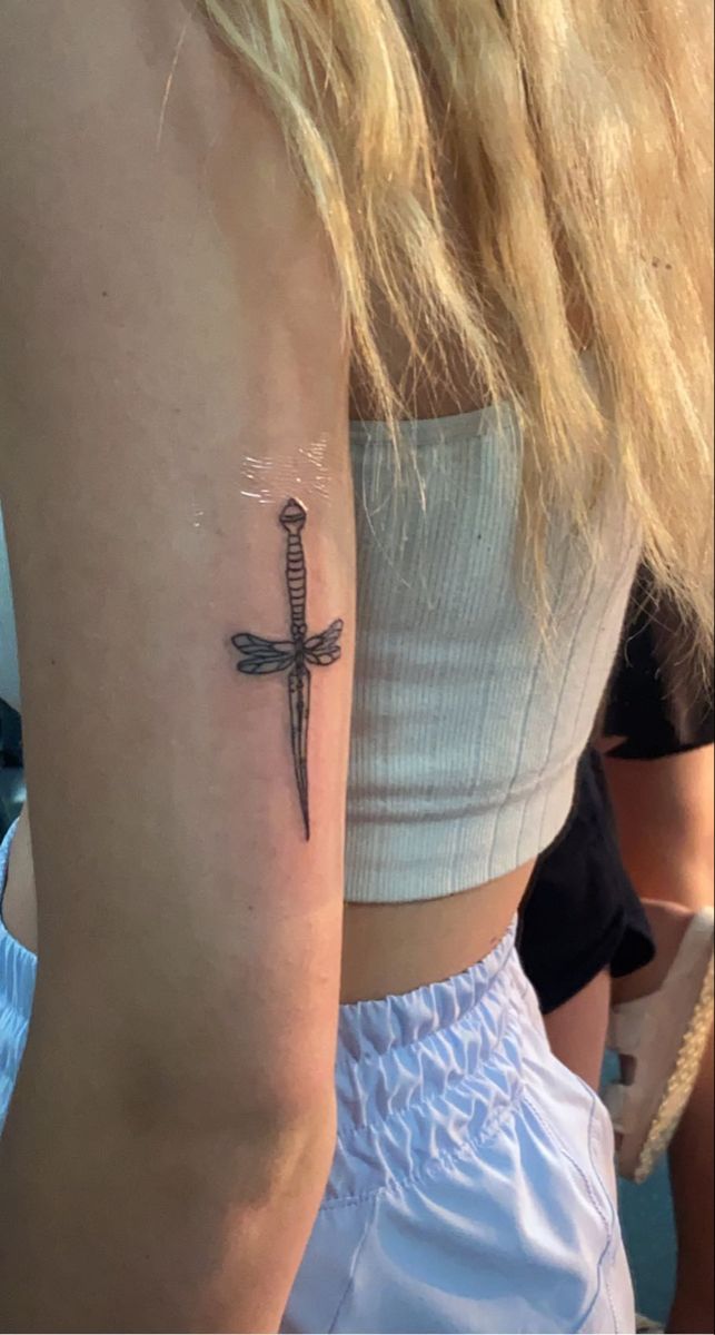 a woman's arm with a cross tattoo on the left side of her arm