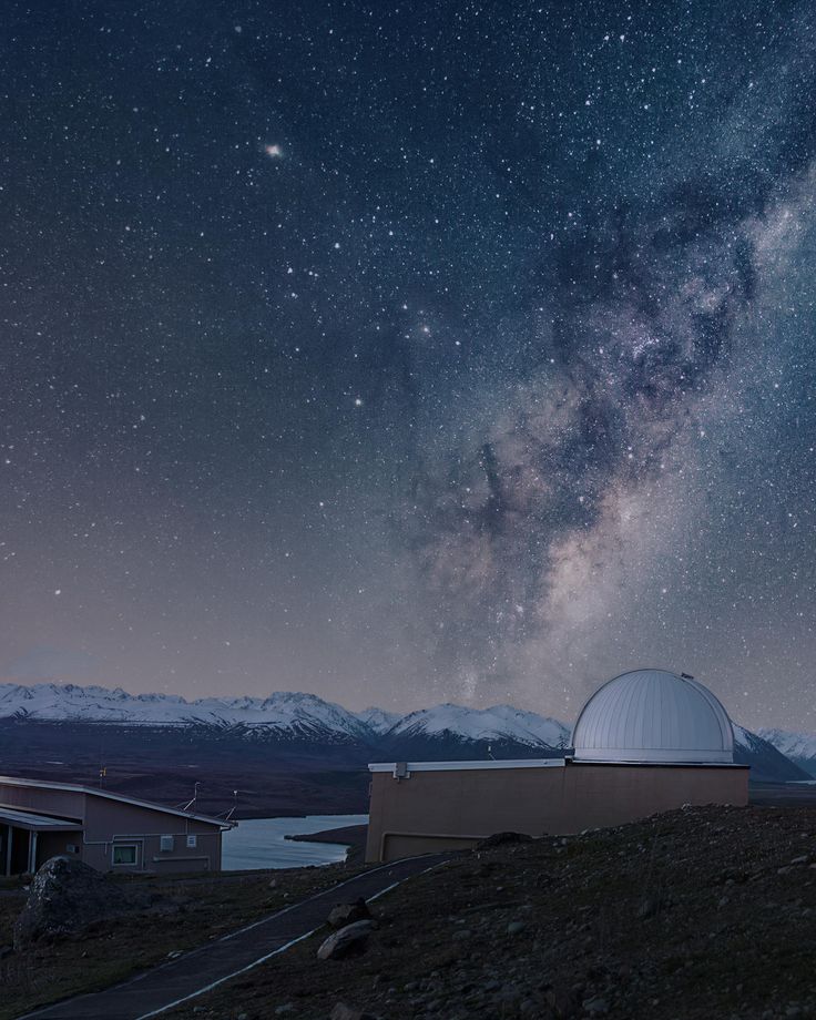 the night sky is filled with stars, and there are two telescopes in front of it