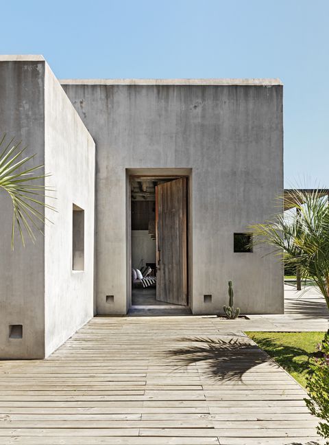 an entrance to a house with wooden floors and palm trees in the front yard area