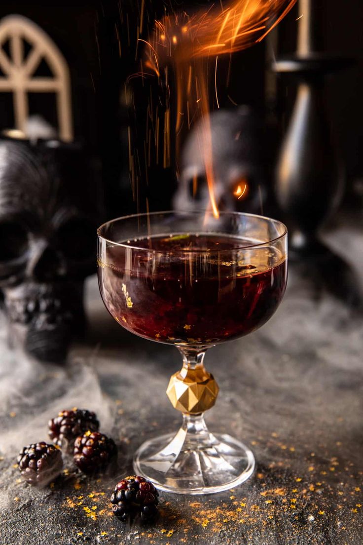 a glass filled with liquid sitting on top of a table next to some blackberries