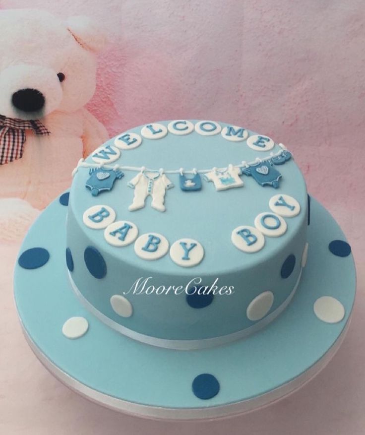 a blue and white cake sitting on top of a table next to a teddy bear