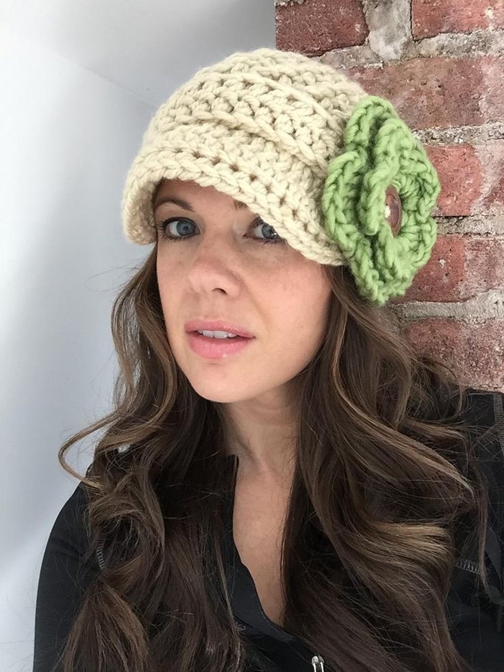 a woman wearing a crocheted hat with a flower on it's side