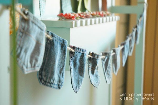 denim pants hanging on a clothes line with flowers in vases next to the window