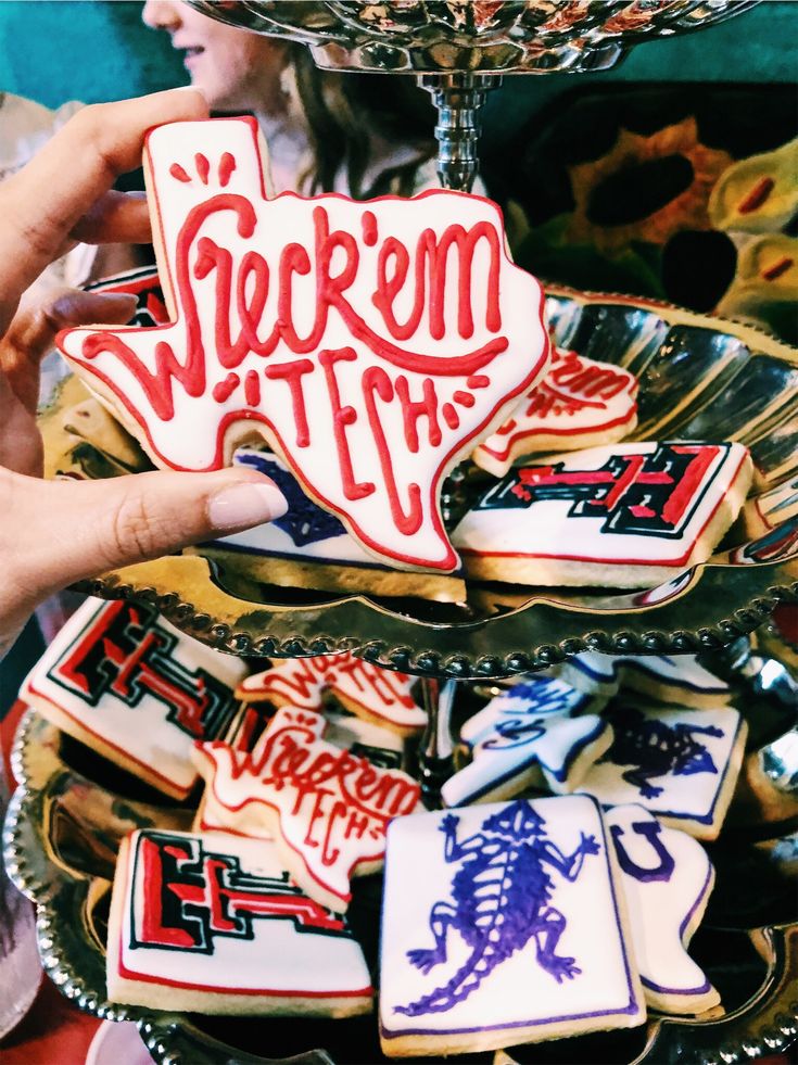 someone holding up some decorated cookies in front of a glass plate with the word victory on it