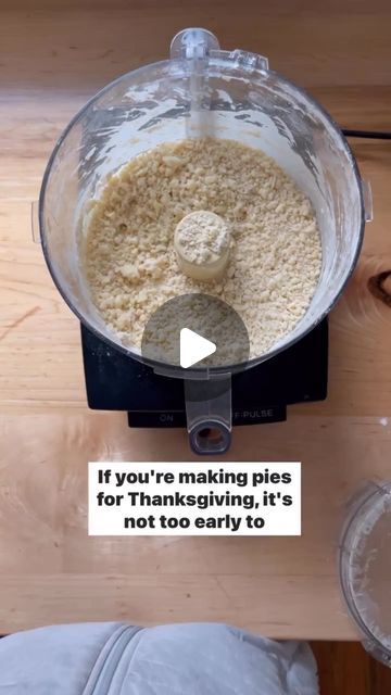 a food processor filled with ingredients on top of a wooden table next to a glass bowl