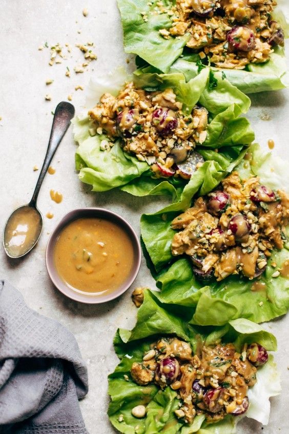 lettuce wraps with peanut butter and cranberry toppings on a white surface