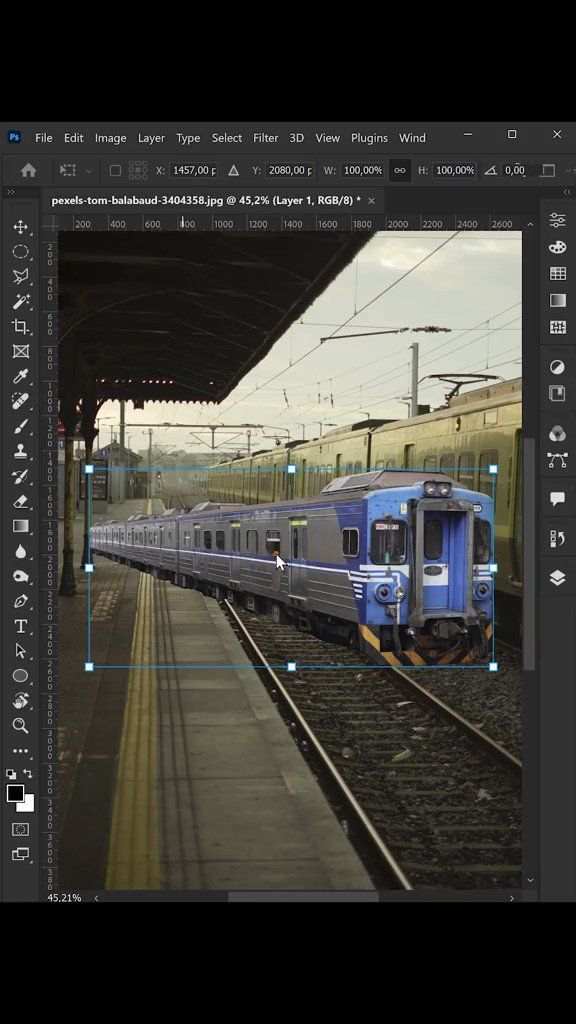 a blue and silver train traveling down tracks next to a loading platform at a train station