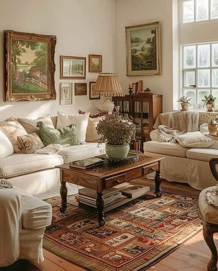 a living room filled with furniture and paintings on the wall next to a table in front of a window