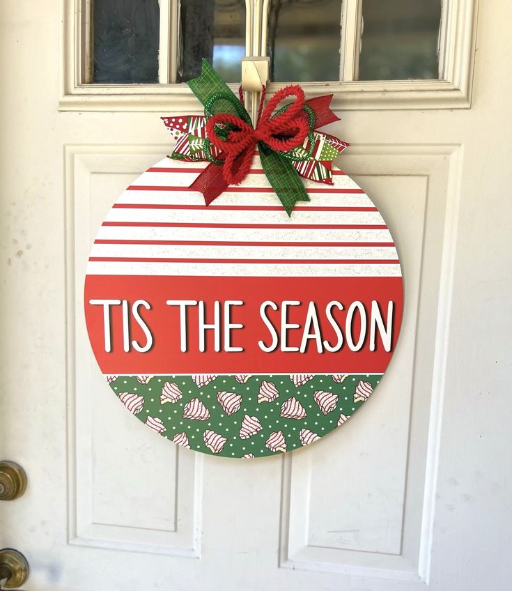 a christmas ornament hanging on a door with the words tis the season painted on it