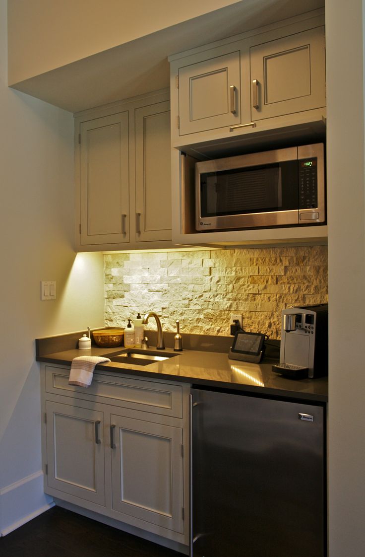 a small kitchen with white cabinets and black counter tops is lit by the light coming through the window