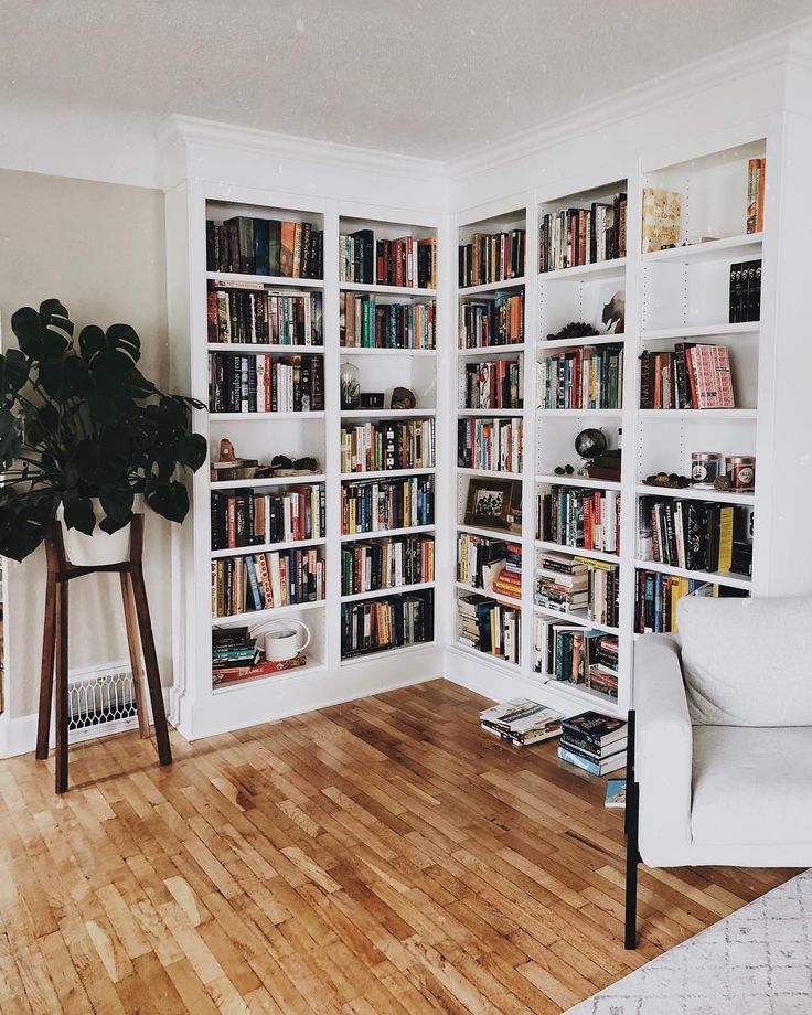 a living room filled with lots of books on white bookcases next to a chair