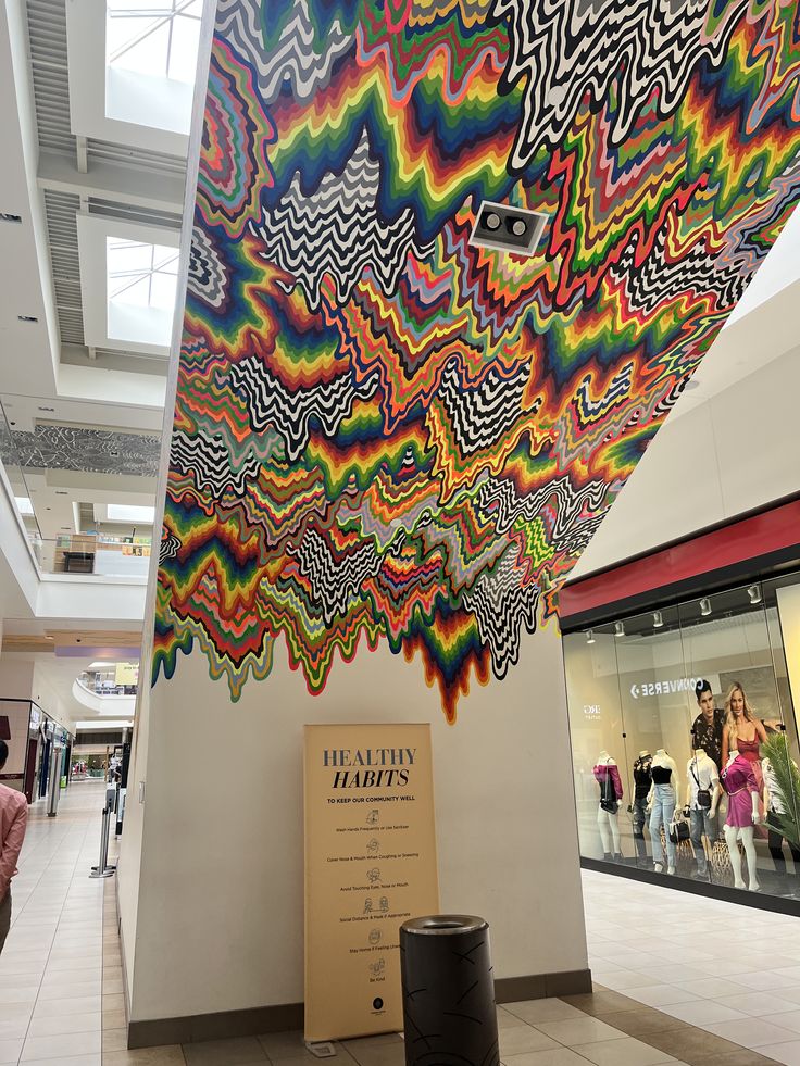 a colorful mural on the side of a building with people walking by in the background