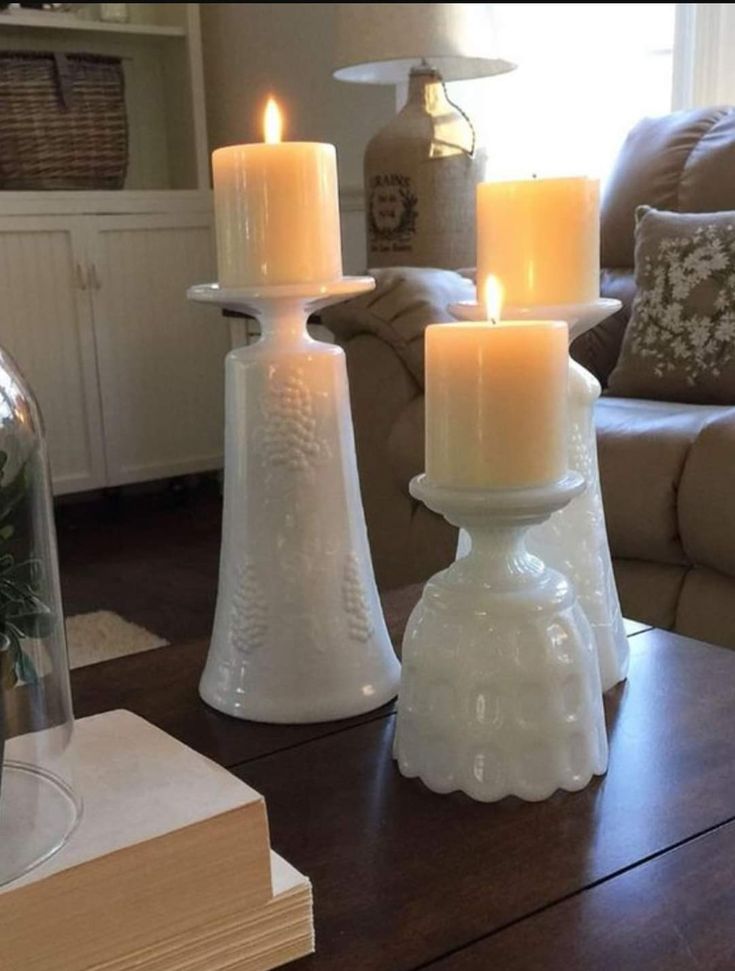 three candles sitting on top of a wooden table in front of a couch and coffee table