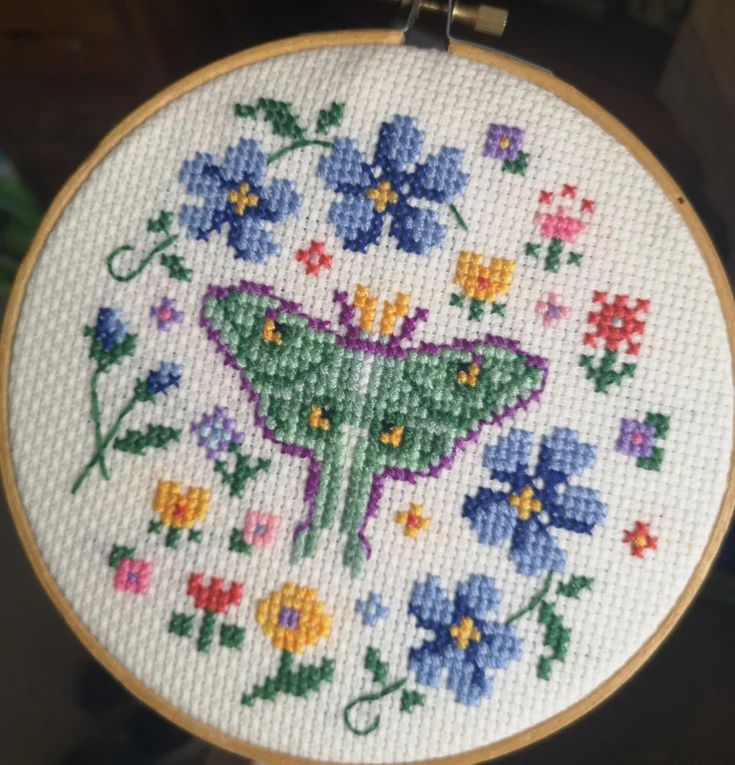 a close up of a embroidery on a hoop with flowers and a butterfly in it