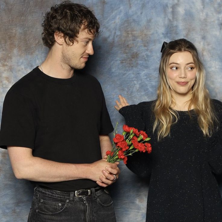 a man and woman standing next to each other with flowers in front of their faces