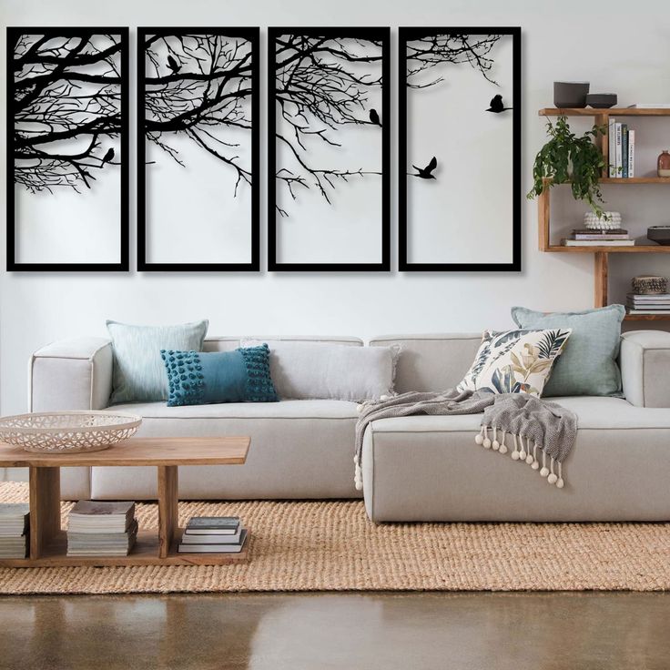 three black and white paintings on the wall above a couch in a living room with a coffee table