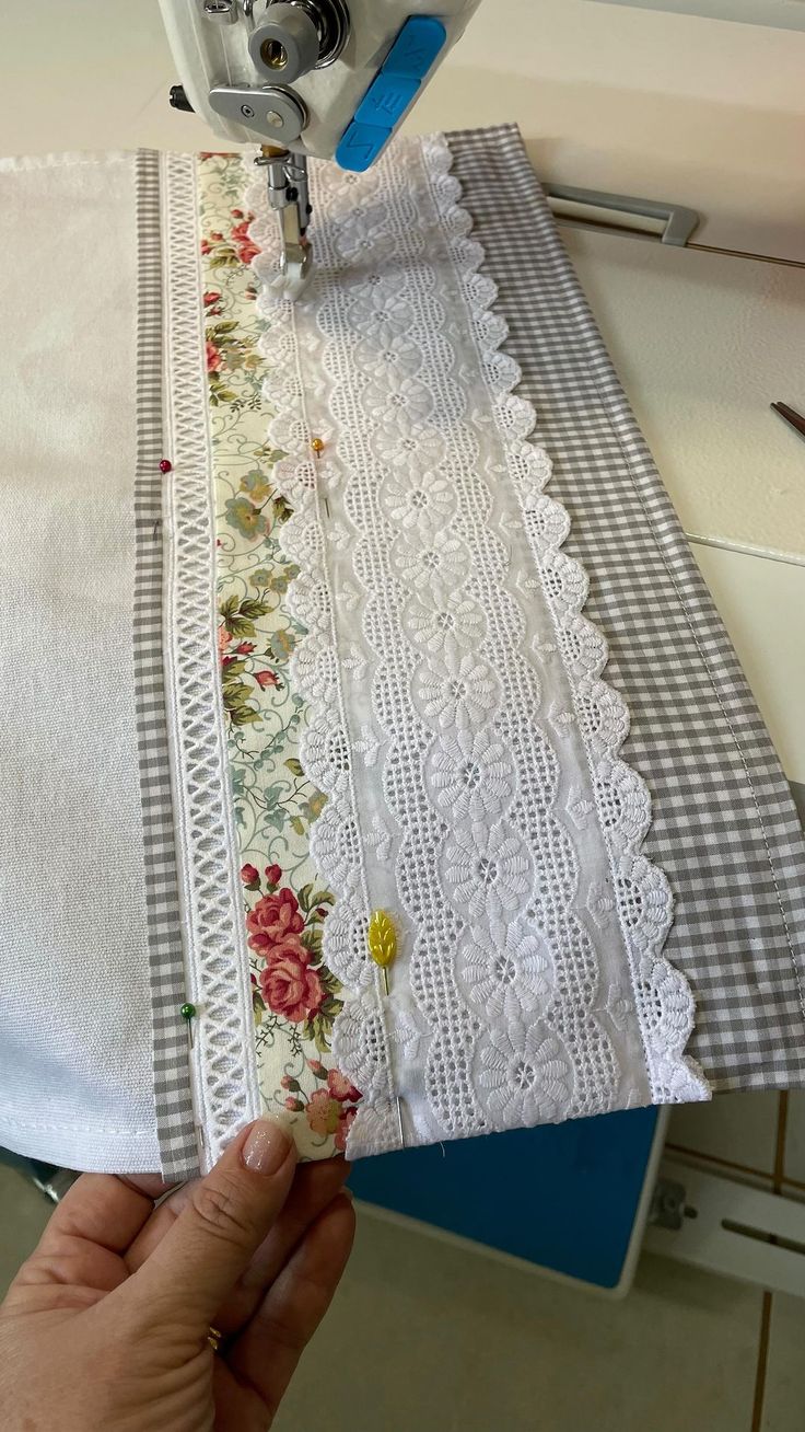 someone is using a sewing machine to sew on some white fabric with flowers and gingham