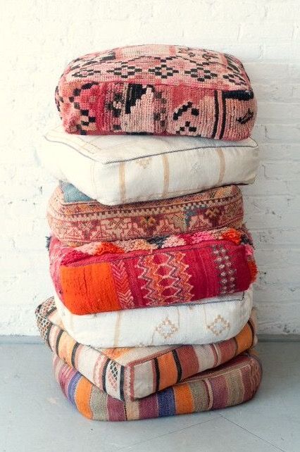 a stack of pillows sitting on top of each other in front of a white brick wall