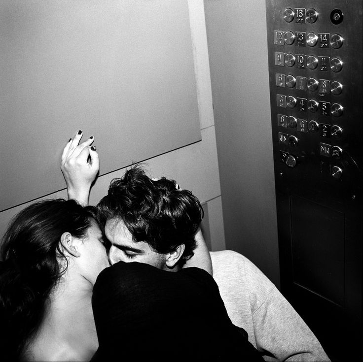 black and white photograph of two people laying on a bed with their backs to each other