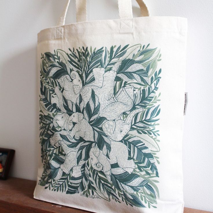 a tote bag with an image of flowers and leaves on it sitting on a shelf