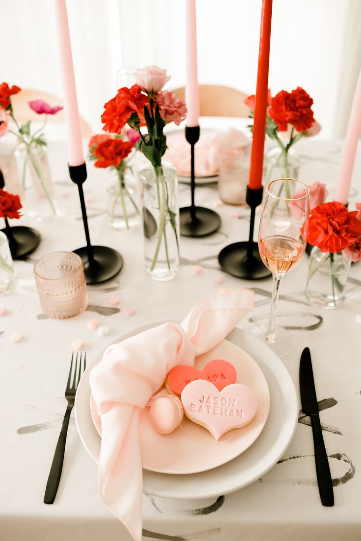 the table is set with candles, plates and napkins on it for valentine's day