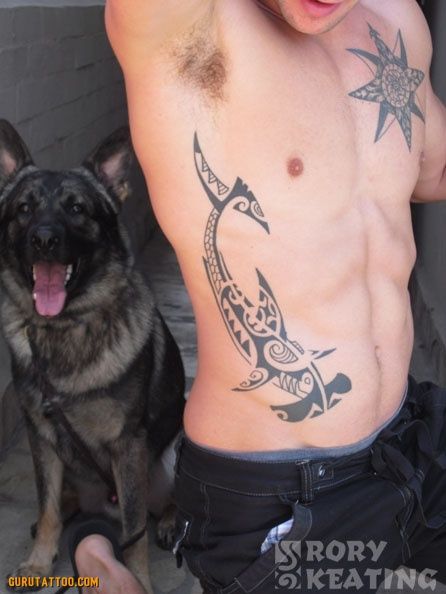 a man with a tattoo on his chest next to a black and brown dog,