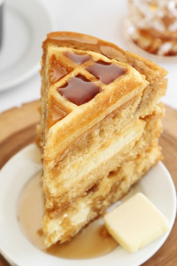 a stack of waffles sitting on top of a white plate next to a cup of coffee