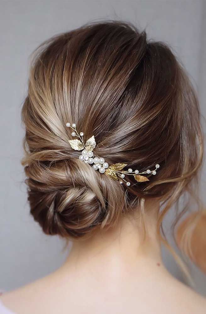 a woman wearing a hair comb with flowers in it's back and her hair pulled up into a low bun