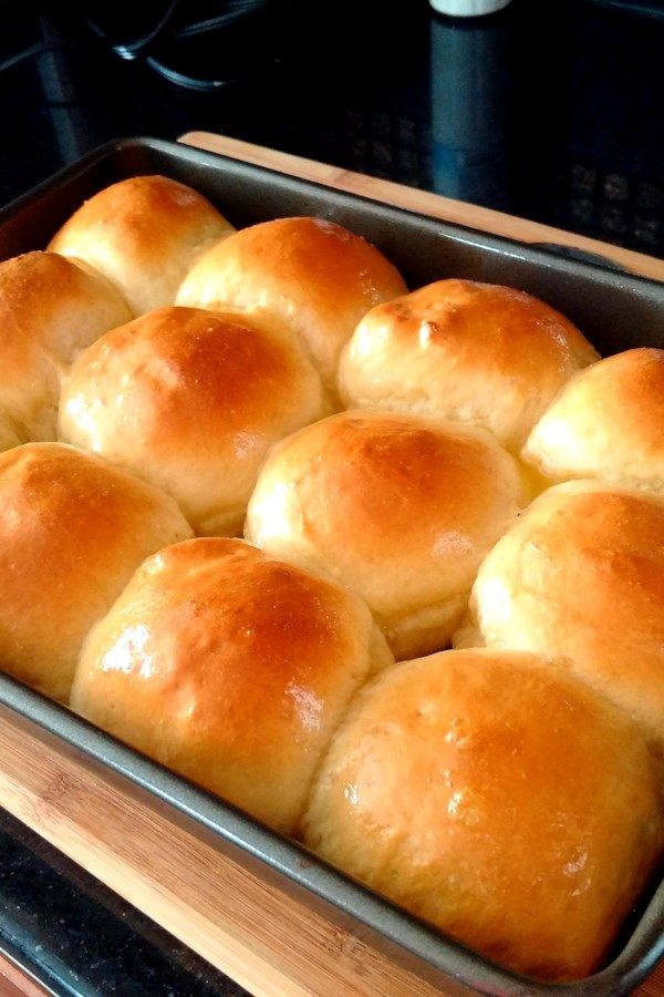 a baking pan filled with rolls sitting on top of a wooden counter next to an oven