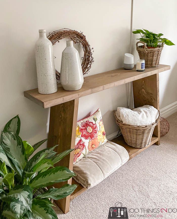 a wooden shelf with two vases on top of it next to a potted plant