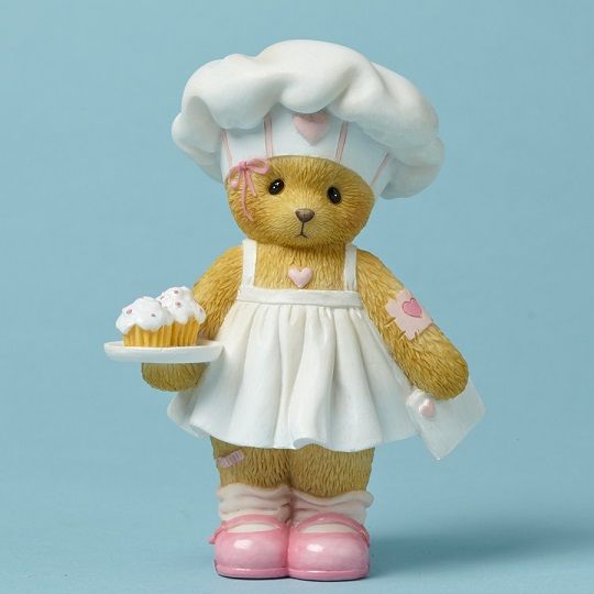 a teddy bear dressed as a chef holding a cupcake