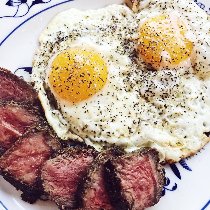 steak and eggs on a plate with black pepper sprinkled on the top,