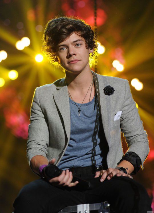 a young man sitting on top of a chair in front of bright lights and lighting behind him