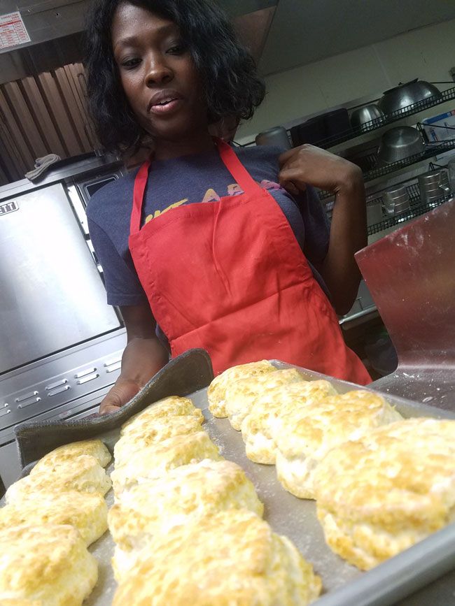 a woman in an apron is making biscuits