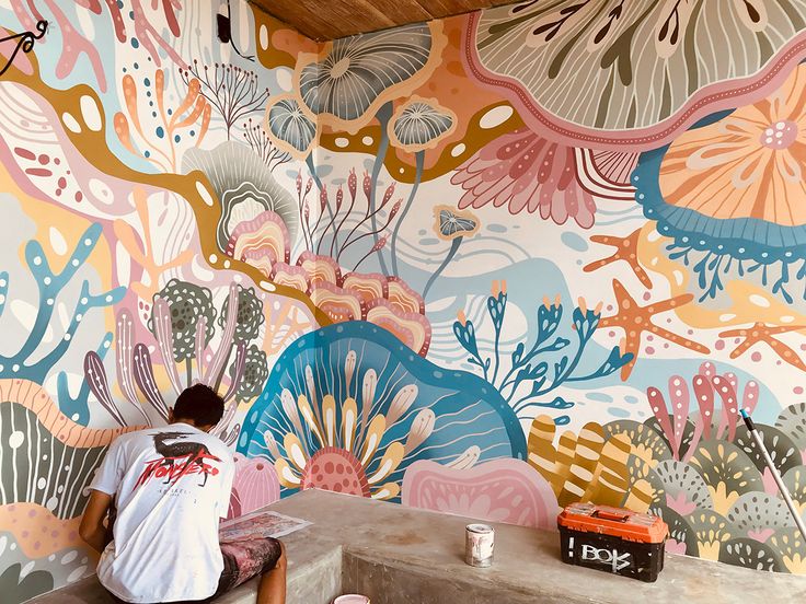 a person sitting on a bench in front of a colorful wall