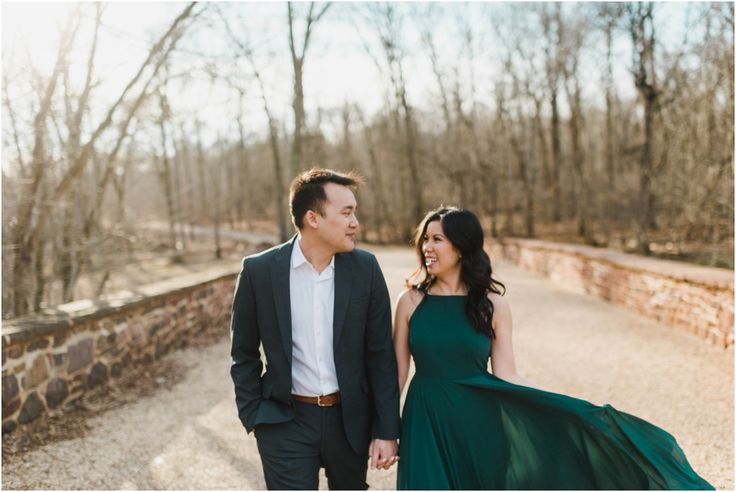 a man and woman walking down a road holding hands