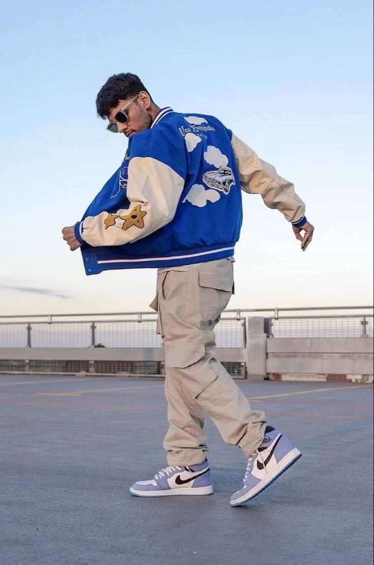 a young man wearing a blue jacket and white sneakers walking across an empty parking lot