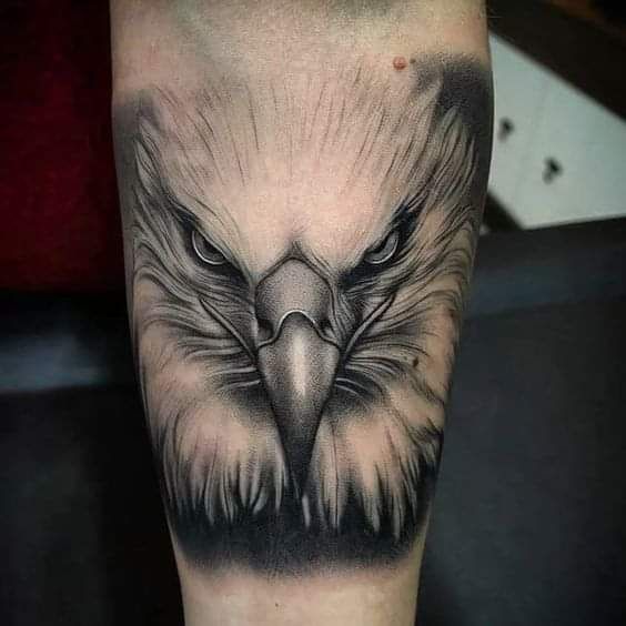 an eagle tattoo on the leg with black and grey ink, it looks like he's looking at something