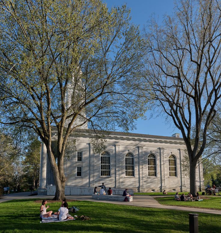 two people sitting on the grass in front of a building