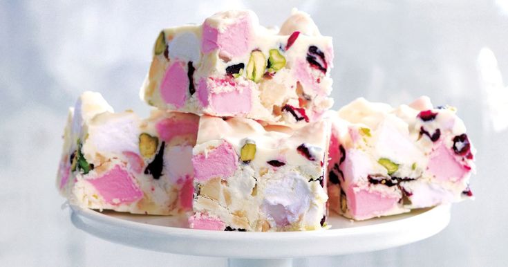 a white plate topped with pieces of cake covered in pink and green frosting on top of a table