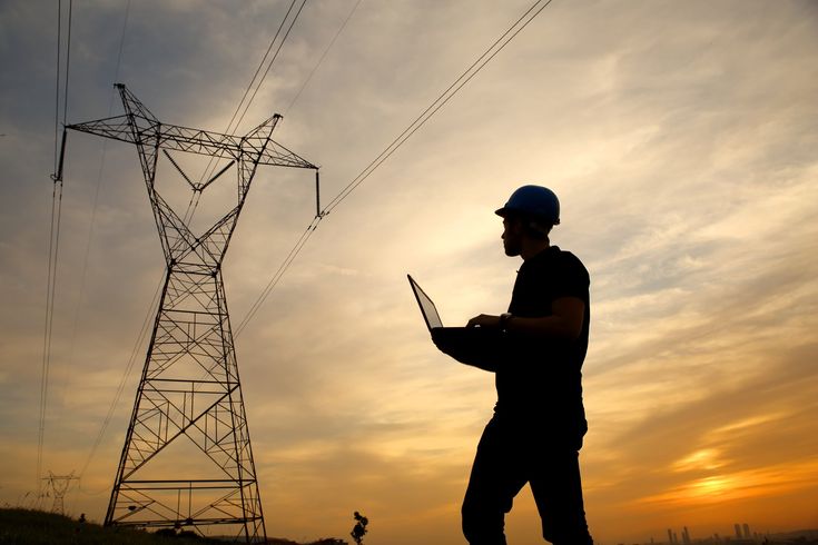 a man standing in front of power lines with his laptop