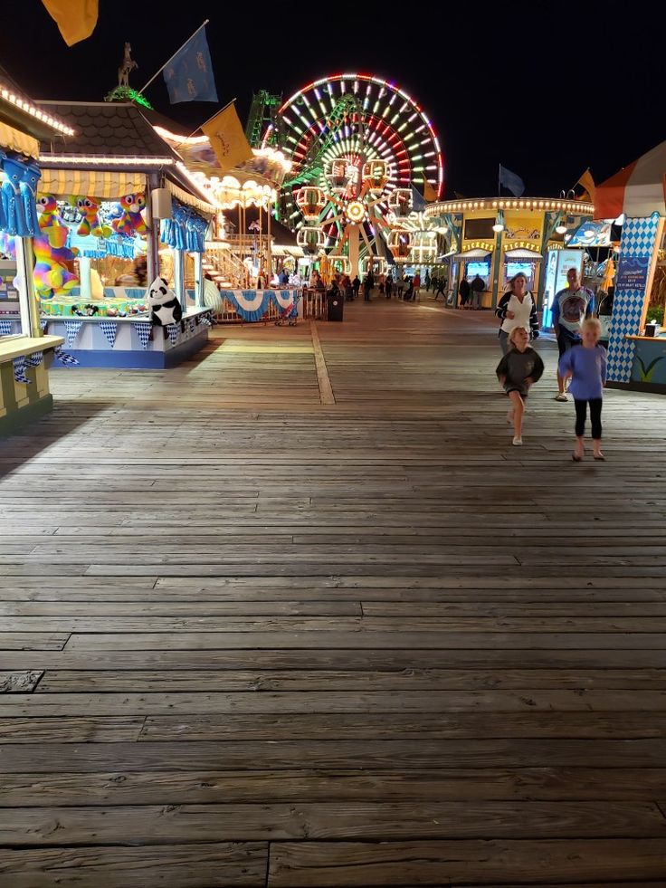 people are walking around an amusement park at night