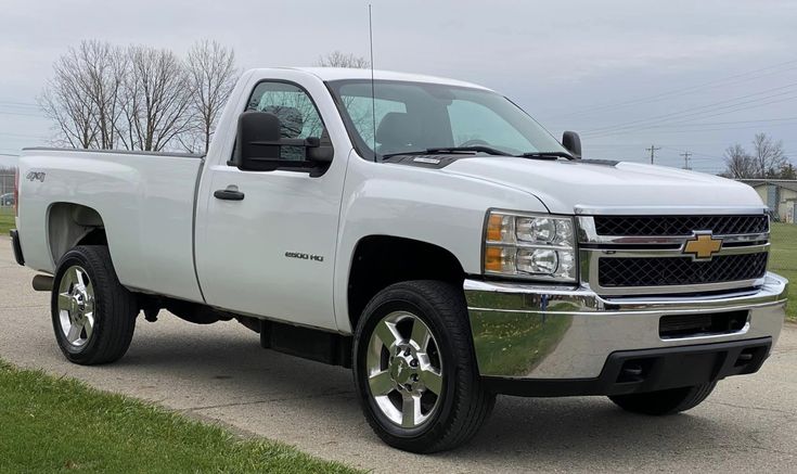 a white truck is parked on the side of the road in front of some grass