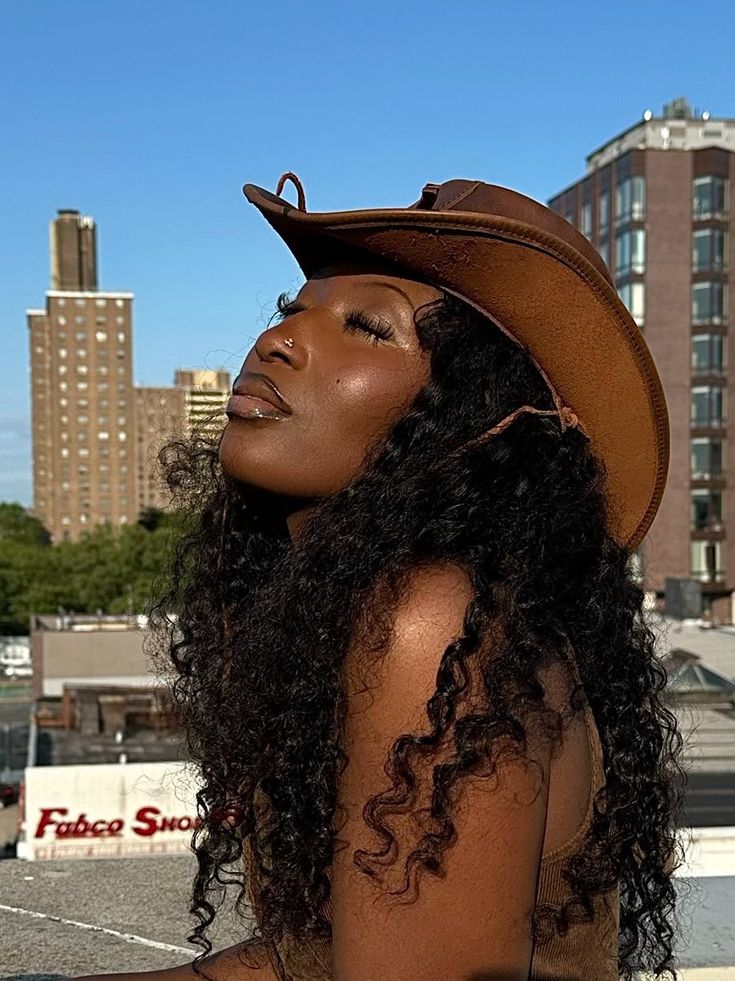 a woman with curly hair wearing a brown hat