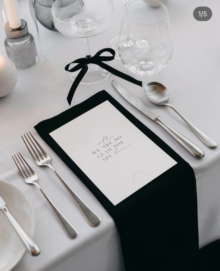 a place setting with silverware and napkins on a white tableclothed table