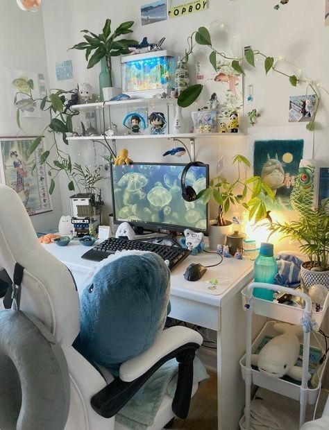 a computer desk with two monitors and a keyboard on it in a room filled with plants