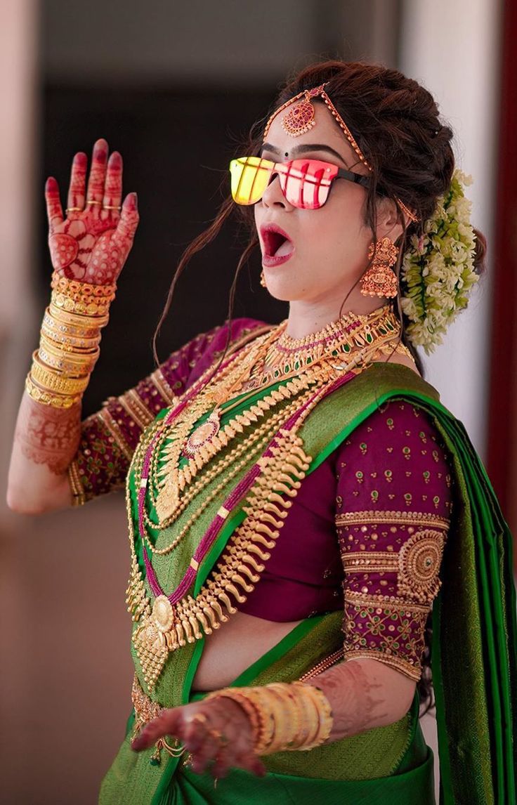 a woman in a green and red sari holding her hand up