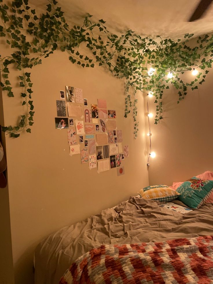 an unmade bed with ivy growing on the wall and lights hanging from the ceiling